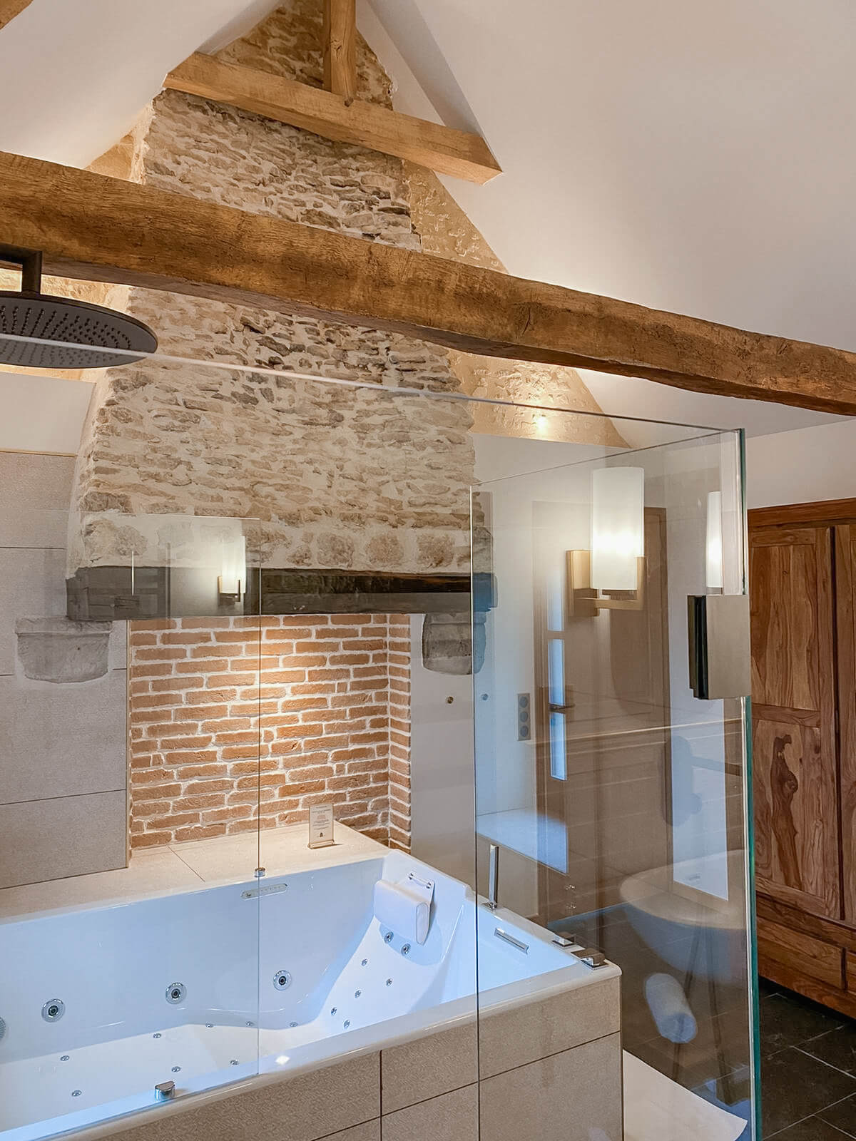 Réhabilitation d'un ancien four à pain en chambre d'hôtes salle de bain balnéo avec grande douche et spa Réhabilitation d'un ancien four à pain en chambre d'hôtes chaleureuse avec poutres apparentes, mur en pierre et lumière naturelle, salle de bain balnéo avec grande douche et spa, au Merlerault dans le perche normand