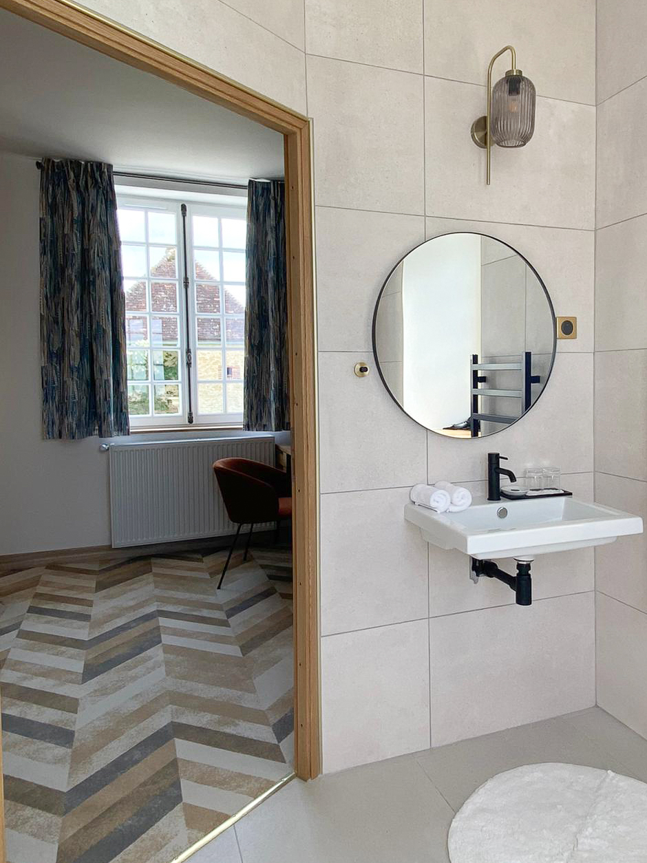 Domaine de Prestal rénovation maisons d'hotes chambre accessible PMR, salle de bain spacieuse Rénovation d’une maison ancienne en chambre d’hôtes au Merlerault dans le perche normand, accessible PMR, salle de bain spacieuse avec carrelage grand format minéral beige, luminaire et interrupteur laiton