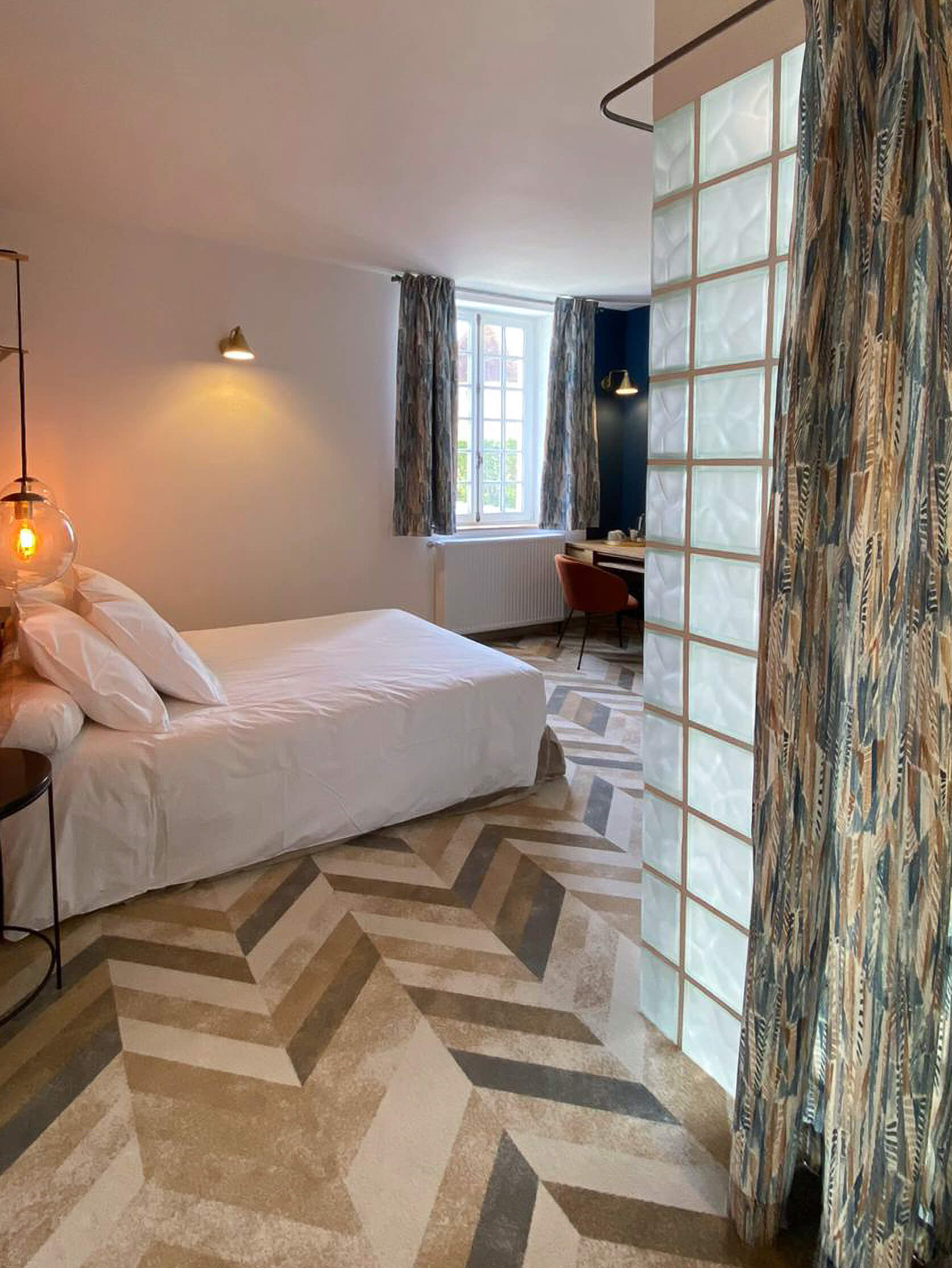 Domaine de Prestal rénovation maisons d'hotes chambre, moquette chevron, rideaux tissu ethnique, carreaux de verre Rénovation d’une maison ancienne en chambre d’hôtes au Merlerault dans le perche normand, avec des rideaux en tissu ethnique de plumes bleu et marron, un mur en carreaux de verre pour séparer la salle de bain