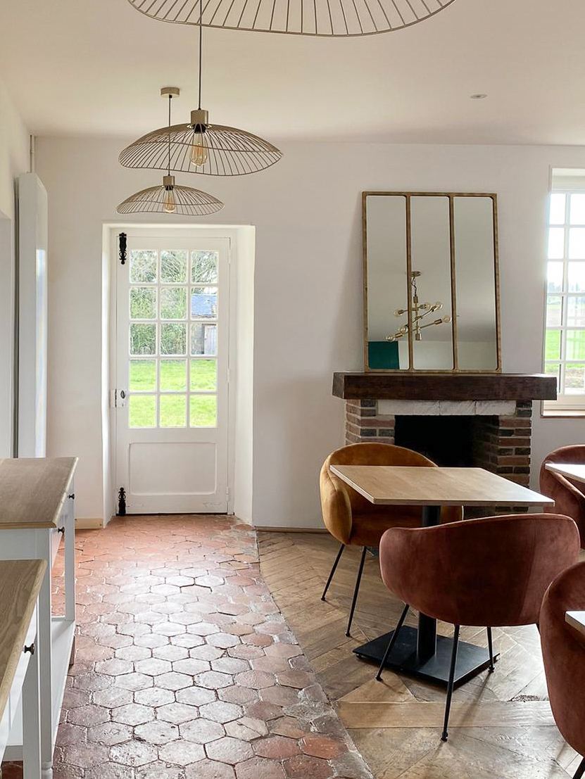 Domaine de Prestal rénovation maisons d'hotes, salle du petit déjeuner, tomettes et parquet d'origine Rénovation d’une maison ancienne en chambre d’hôtes au Merlerault dans le perche normand, salle du petit déjeuner avec du parquet massif associé aux tomettes anciennes d’origine, cheminée en brique avec un miroir en laiton posé, table en bois et fauteuils de table colorés