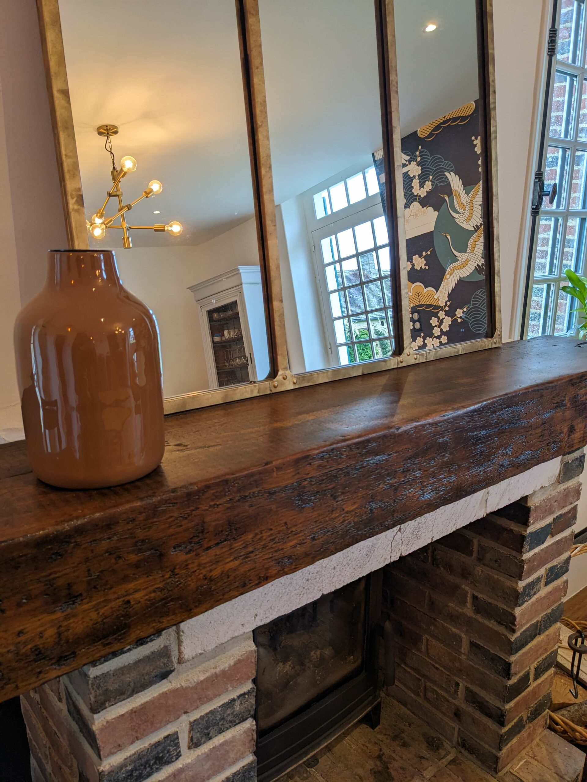 Domaine de Prestal rénovation maisons d'hotes, salle du petit déjeuner, zoom sur la cheminée en brique et bois, miroir laiton Rénovation d’une maison ancienne en chambre d’hôtes au Merlerault dans le perche normand, salle du petit déjeuner avec détail de la cheminée en brique, miroir laiton posé