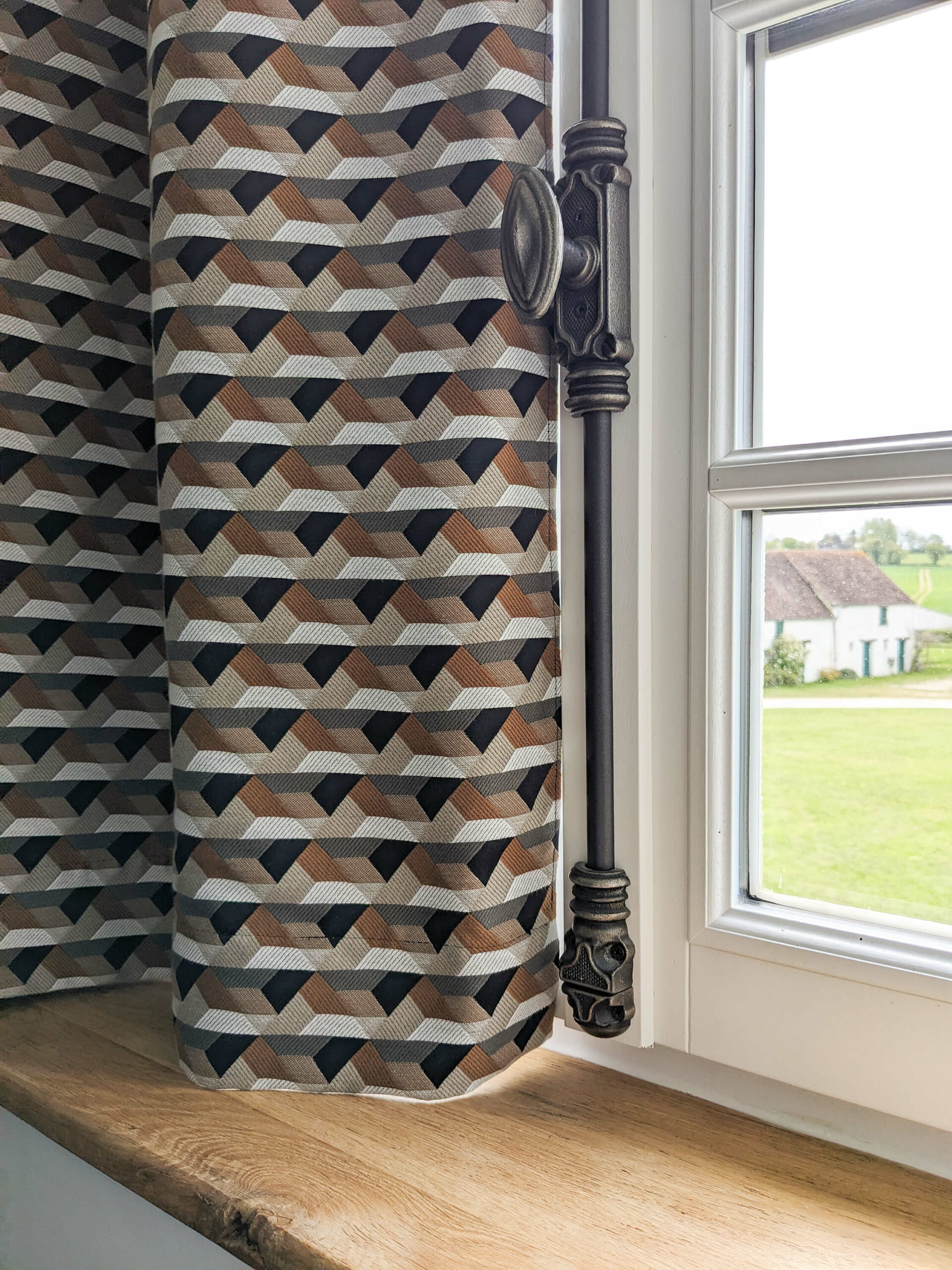 Rénovation d’une maison ancienne en chambre d’hôtes, détail rideau à motifs géométriques et crémone finition canon de fusil