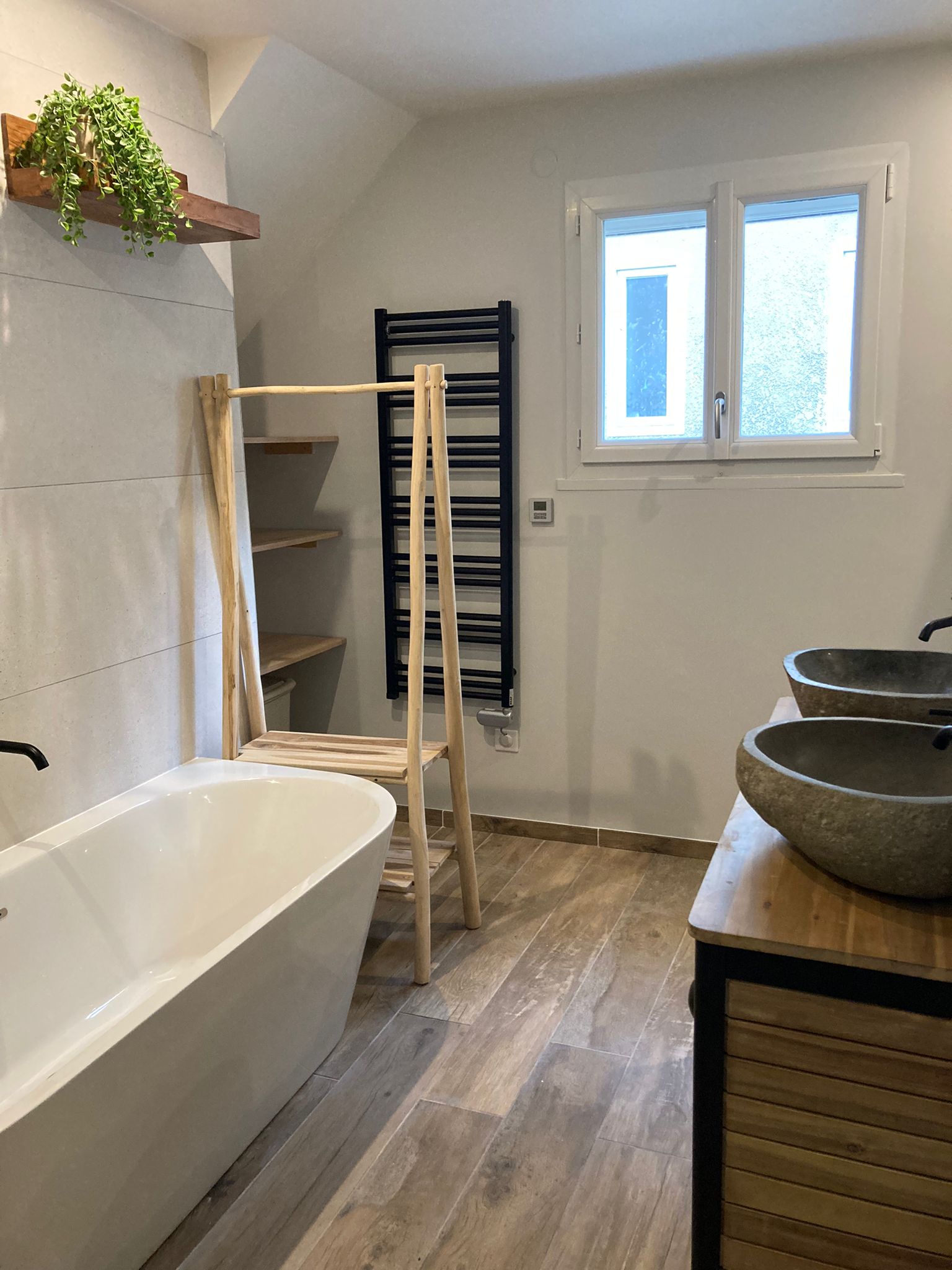 Agrandissement et rénovation d’une salle de bain familiale esprit nature et zen, grande baignoire semi-ilot, mur vert, carrelage en pierre naturelle beige, double vasque en pierre naturelle et meuble en bois massif, à Orsay en Essonne