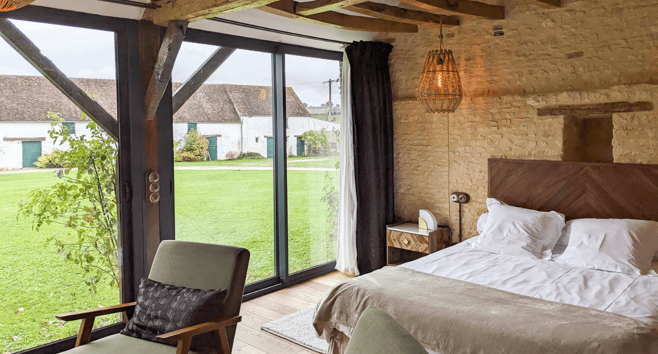 Réhabilitation d'un ancien four à pain en chambre d'hôtes chaleureuse avec poutres apparentes, mur en pierre et lumière naturelle, au Merlerault dans le perche normand