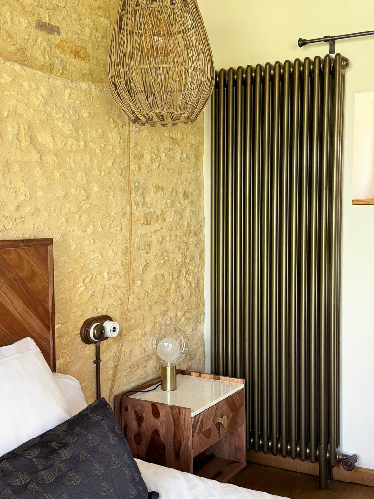 Réhabilitation d'un ancien four à pain en chambre d'hôtes chaleureuse avec détail sur la lampe de chevet en laiton et verre, table de chevet en bois massif avec plateau de marbre blanc, appareillage électrique en bois et porcelaine, radiateur en fonte bronze, au Merlerault dans le perche normand