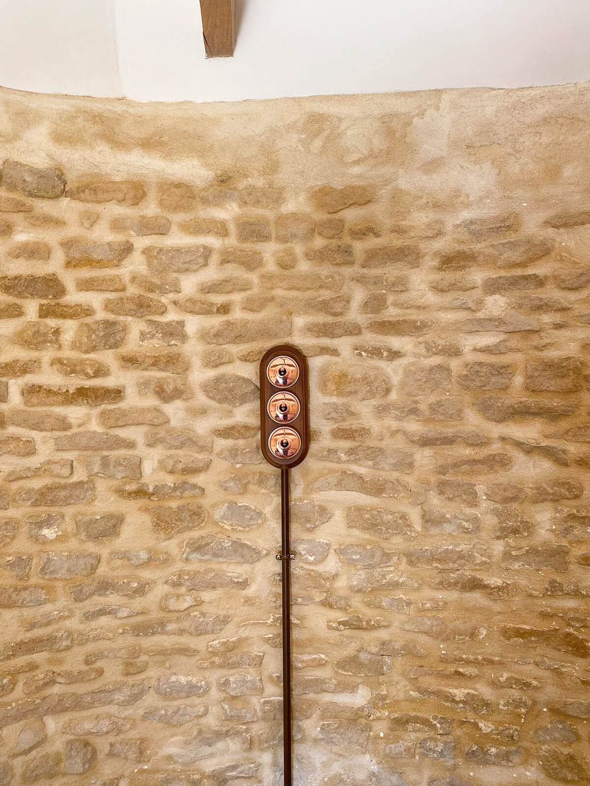 Domaine de Prestal rénovation ancien pigeonnier, détail interrupteur bois et cuivre Réhabilitation d'un ancien pigeonnier en chambre d'hôtes, détail interrupteur bois et cuivre sur un mur de pierre, au Merlerault dans le perche normand