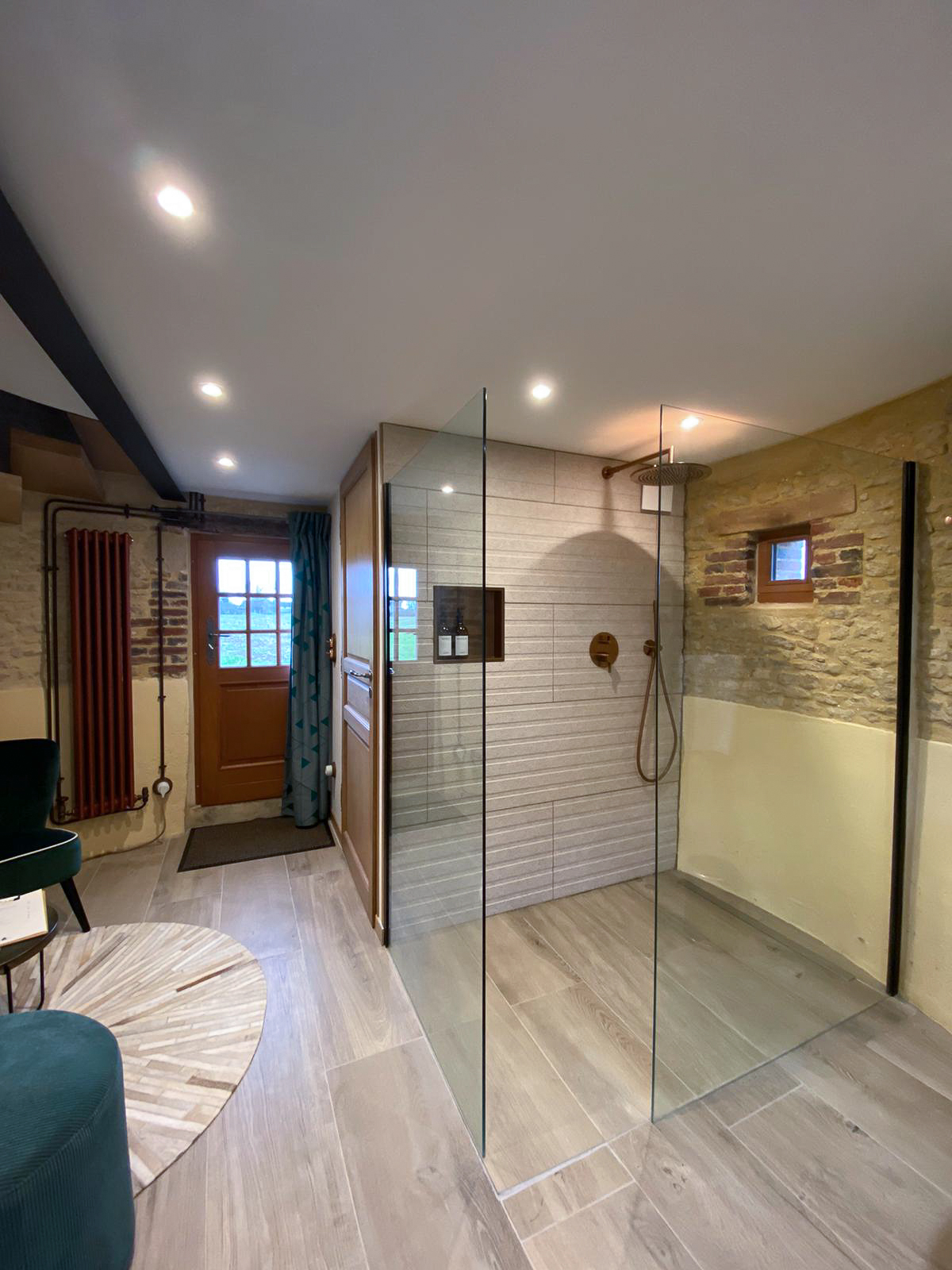 Domaine de Prestal rénovation ancien pigeonnier, salle de douche ouverte sur petit salon, douche à l'italienne, mur de pierre Réhabilitation d'un ancien pigeonnier en chambre d'hôtes, salle de douche ouverte avec vasque sur pied en pierre et marbre, robinetterie et détails cuivrés, au Merlerault dans le perche normand