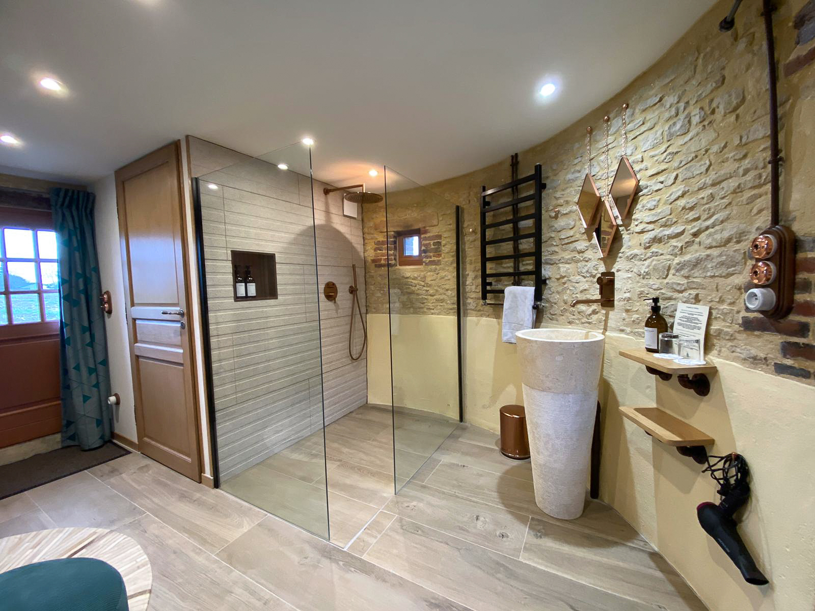 Domaine de Prestal rénovation ancien pigeonnier, salle de douche ouverte Réhabilitation d'un ancien pigeonnier en chambre d'hôtes, salle de douche ouverte avec vasque sur pied en pierre et marbre, robinetterie et détails cuivrés, au Merlerault dans le perche normand
