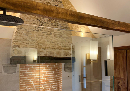 Réhabilitation d'un ancien four à pain en chambre d'hôtes chaleureuse avec poutres apparentes, mur en pierre et lumière naturelle, salle de bain balnéo avec grande douche et spa, au Merlerault dans le perche normand