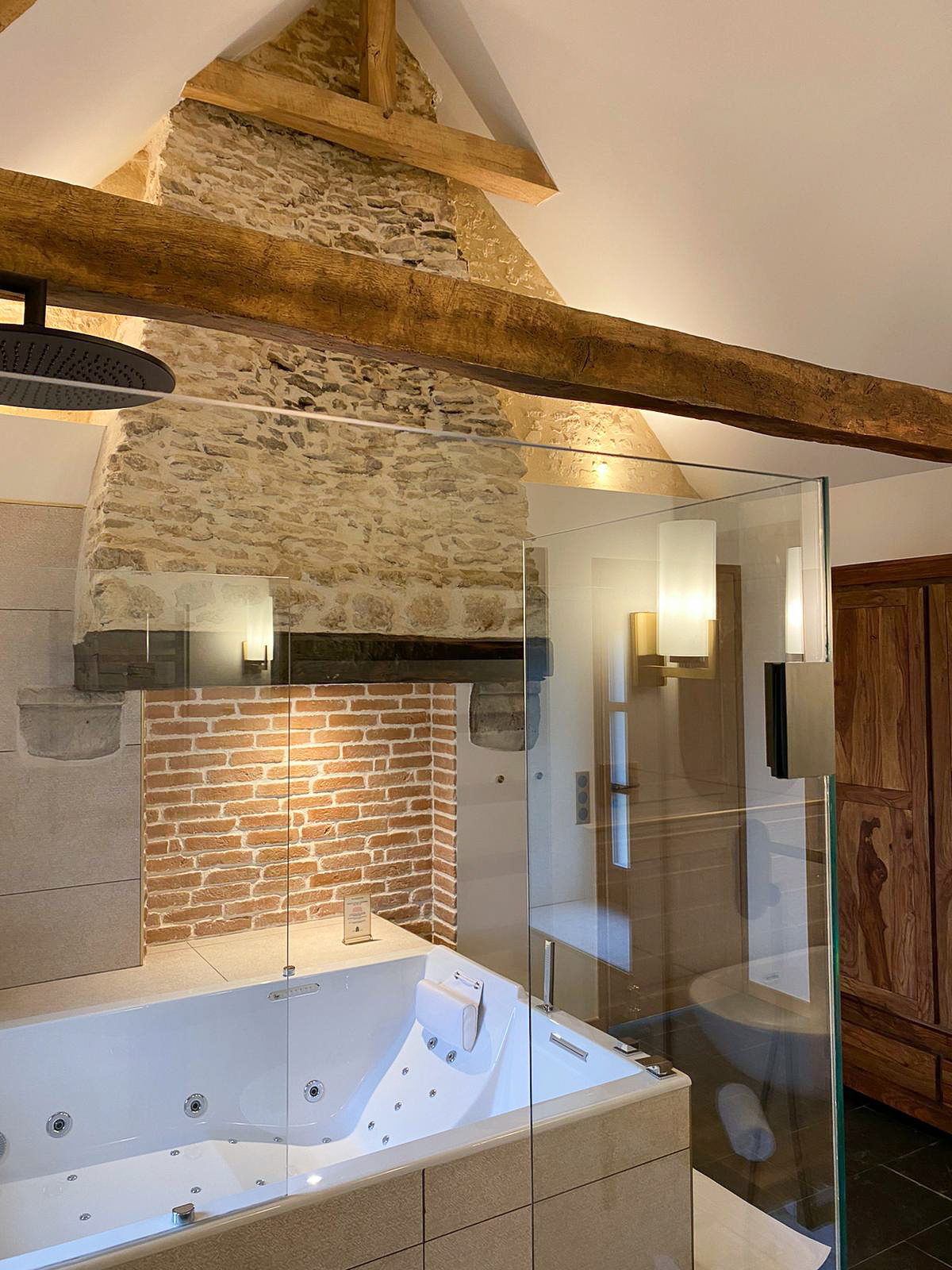 Réhabilitation d'un ancien four à pain en chambre d'hôtes chaleureuse avec poutres apparentes, mur en pierre et lumière naturelle, salle de bain balnéo avec grande douche et spa, au Merlerault dans le perche normand