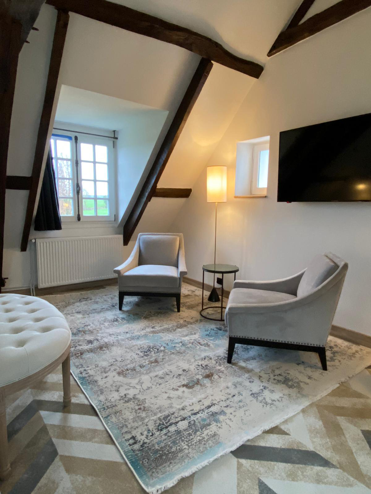 Rénovation d’une maison ancienne en chambre d’hôtes, esprit campagne classique, coin salon, fauteuils crapaud, tapis et table d'appoint Rénovation d’une maison ancienne en chambre d’hôtes au Merlerault dans le perche normand, esprit campagne classique, coin salon avec fauteuils crapaud, tapis et table d'appoint en marbre vert, lampadaire
