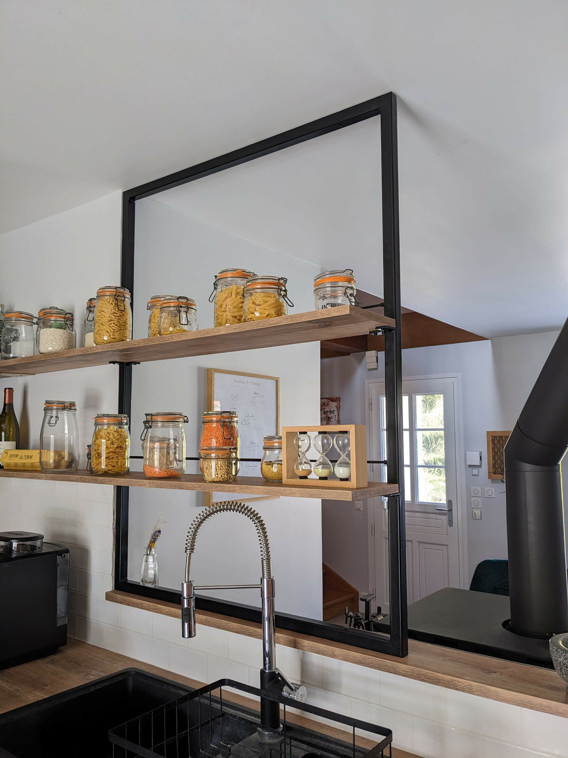 Rénovation d’une maison familiale en campagne essonnienne à Chalo-Saint-Mars, une cuisine complètement rénovée et semi ouverte sur le séjour. détails des étagères sur mesure avec un cadre métallique noir