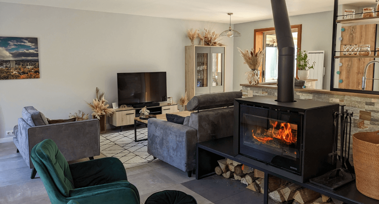 Rénovation d’un séjour en pièce moderne et chaleureuse avec poêle à bois. Décoration naturelle avec touches de bois et bohème pour une ambiance cosy