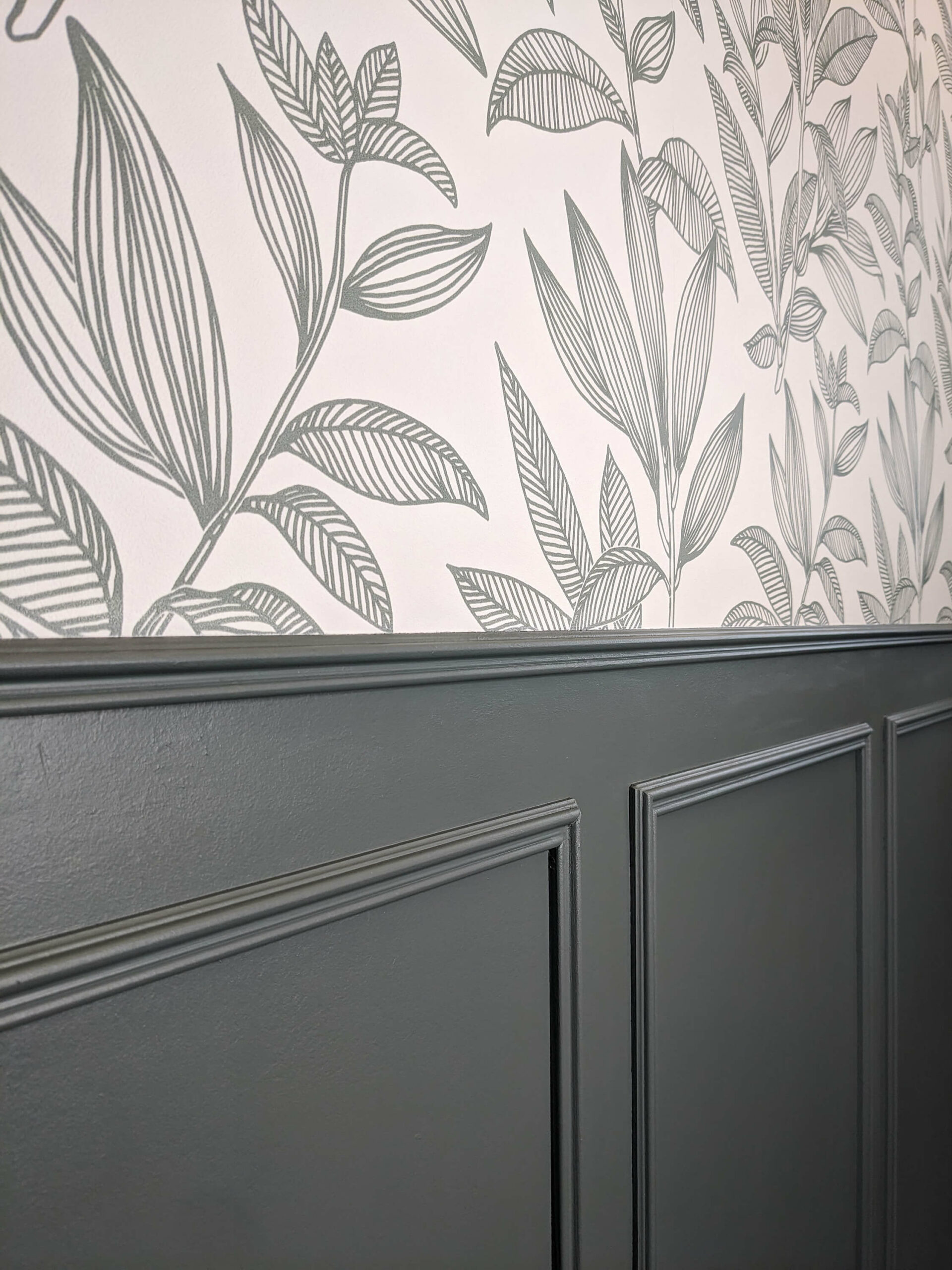 Rénovation d’une maison familiale en campagne essonnienne à Chalo-Saint-Mars, décoration de toilettes style maison ancienne de campagne avec un soubassement en moulures de couleur vert, un papier peint sobre avec des feuilles vertes