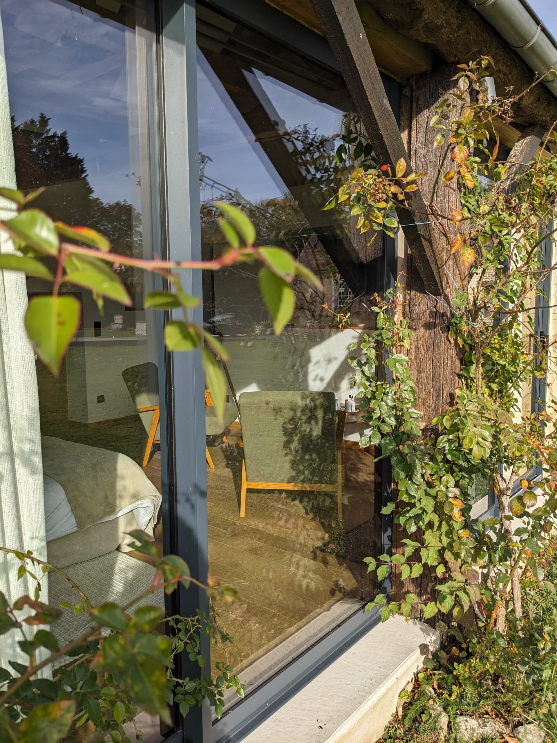 Réhabilitation d'un ancien four à pain en chambre d'hôtes chaleureuse, coin salon vue depuis l'extérieur de la baie vitrée, au Merlerault dans le perche normand