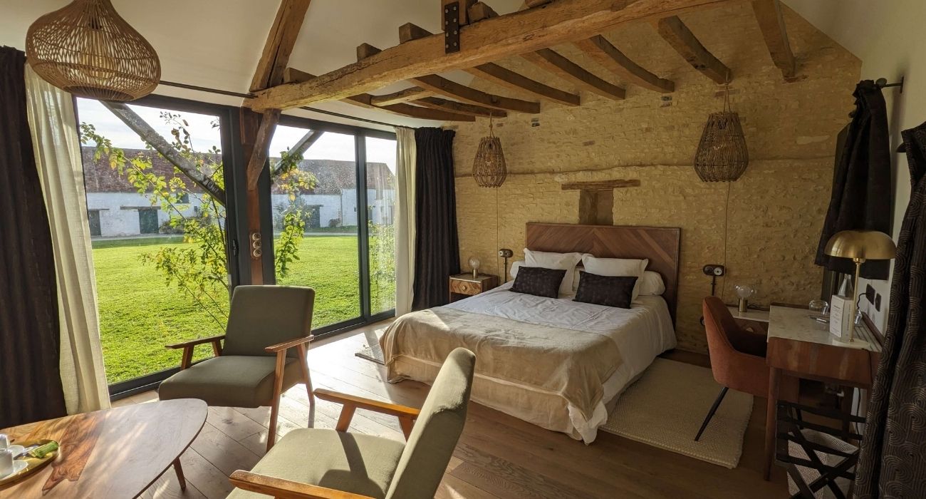 Réhabilitation d'un ancien four à pain en chambre d'hôtes chaleureuse avec poutres apparentes, mur en pierre et lumière naturelle, au Merlerault dans le perche normand