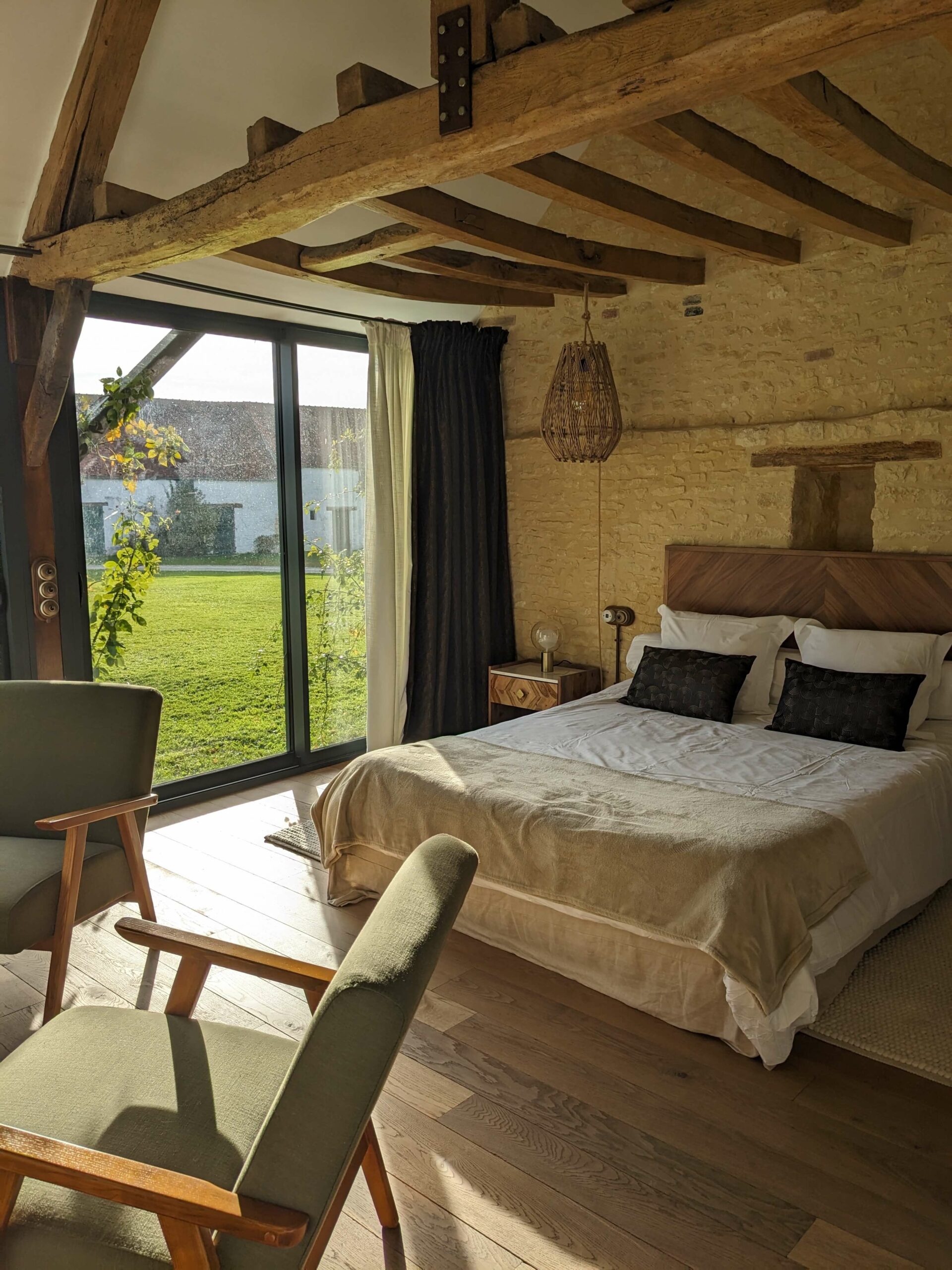 Réhabilitation d'un ancien four à pain en chambre d'hôtes chaleureuse avec poutres apparentes, mur en pierre et lumière naturelle, au Merlerault dans le perche normand