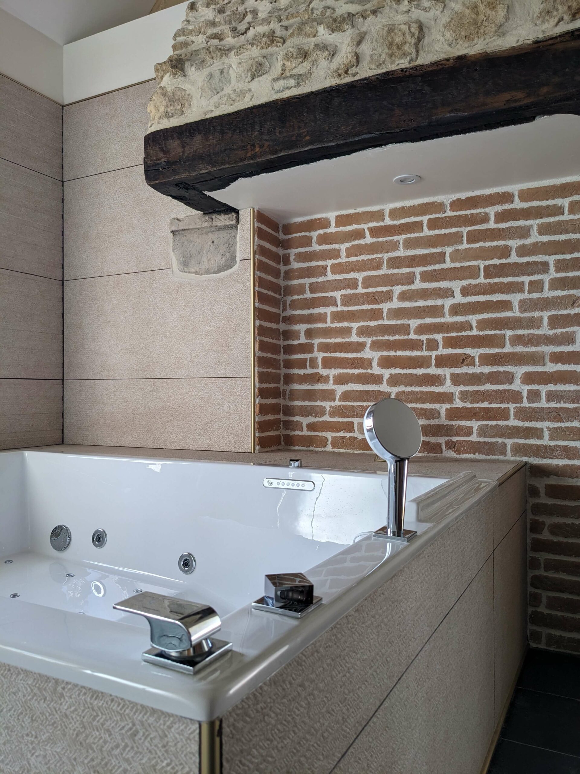 Réhabilitation d'un ancien four à pain en chambre d'hôtes, salle de bain avec baignoire balnéo, mur brique et vieille pierre, cheminée, au Merlerault dans le perche normand