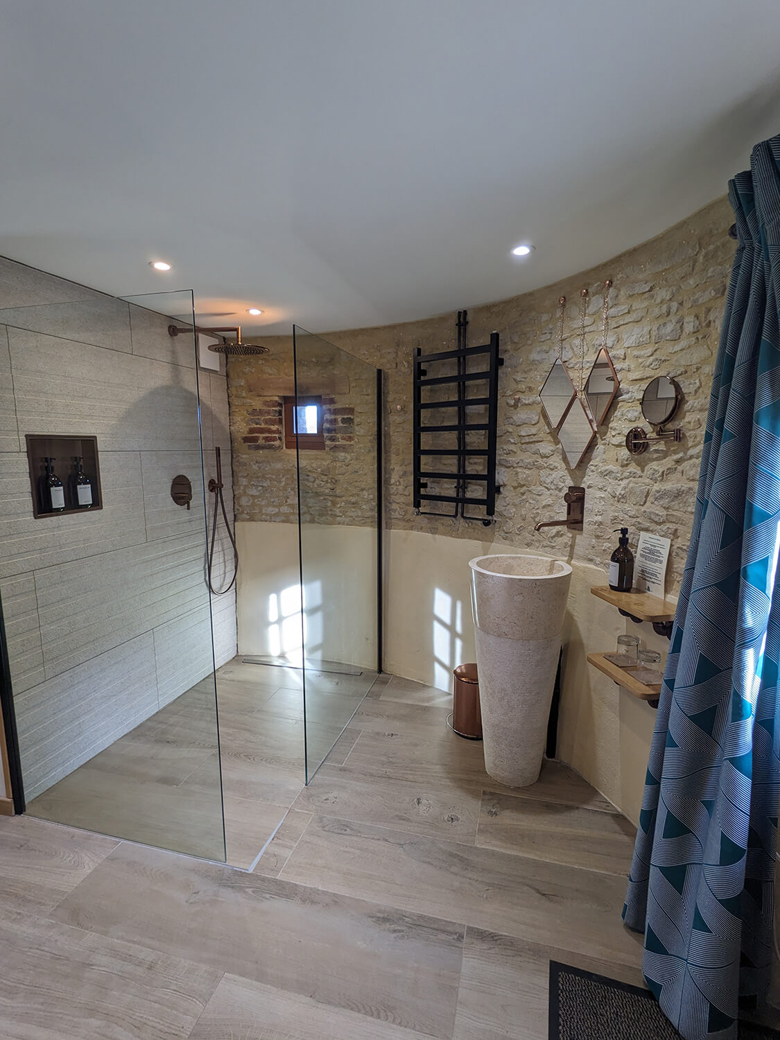 Réhabilitation d'un ancien pigeonnier en chambre d'hôtes, salle de douche ouverte avec vasque sur pied en pierre et marbre, robinetterie et détails cuivrés, au Merlerault dans le perche normand