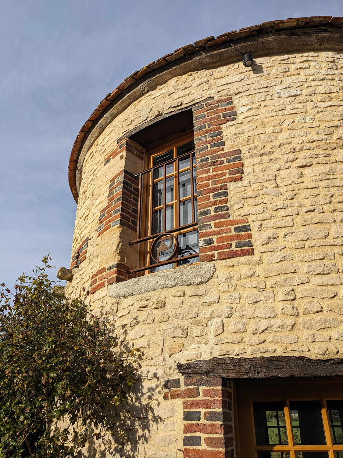 Réhabilitation d'un ancien pigeonnier en chambre d'hôtes, vue extérieure du pigeonnier avec le garde-corps conçu sur mesure reprenant le logo de la maison d’hôtes, au Merlerault dans le perche normand