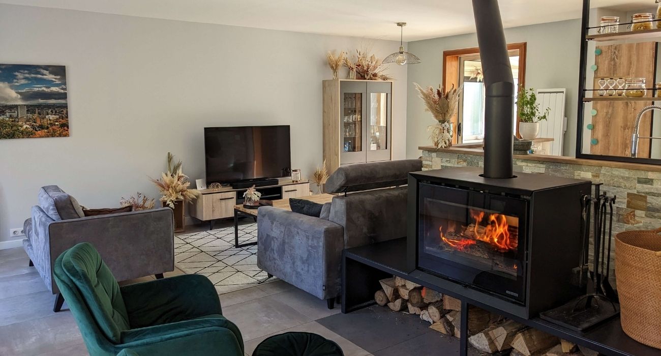 Rénovation d’un séjour en pièce moderne et chaleureuse avec poêle à bois. Décoration naturelle avec touches de bois et bohème pour une ambiance cosy
