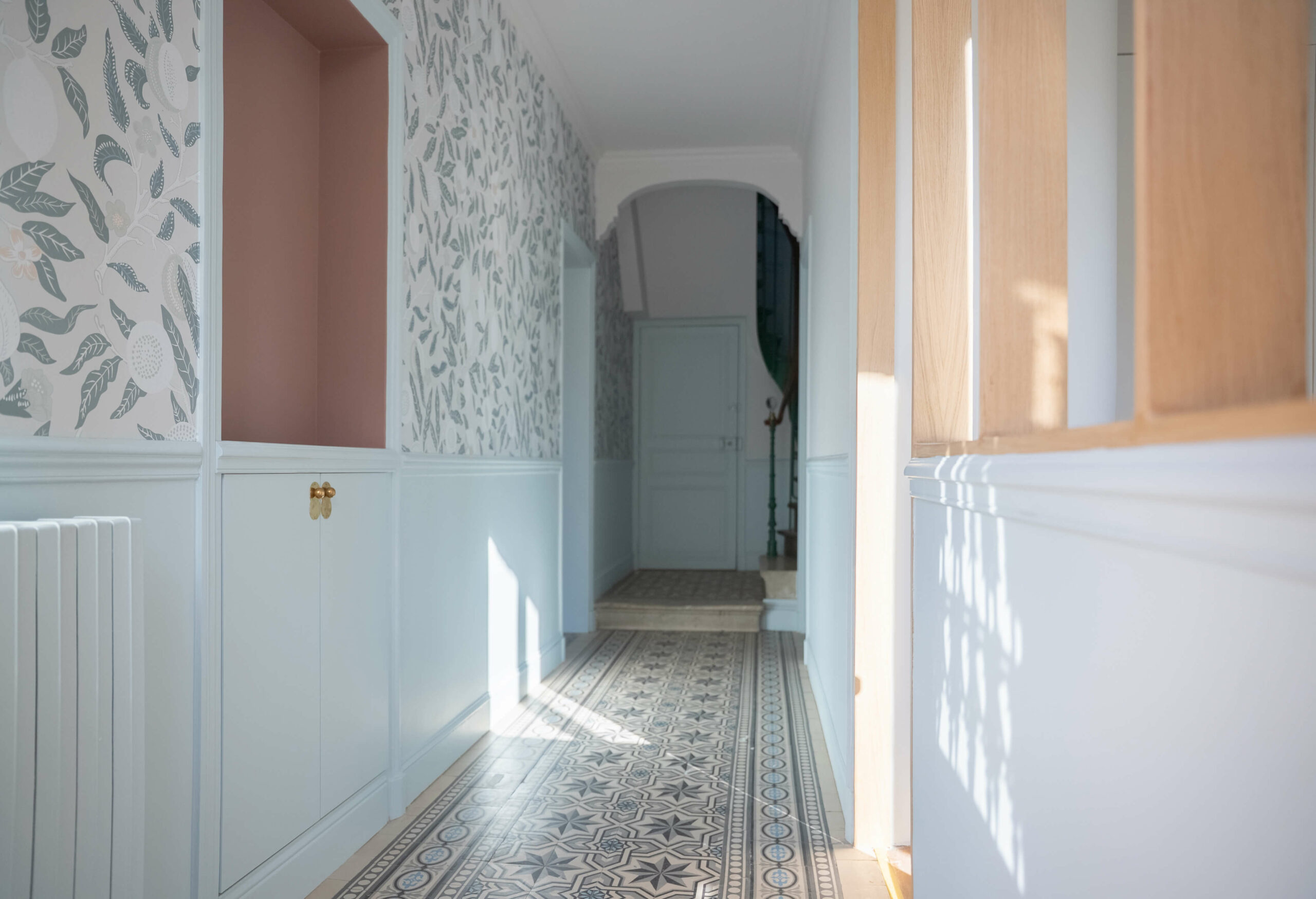 Rénovation d’une maison meulière à Bonnières, retrouver le charme de l’ancien, entrée avec un papier peint floral bleu, soubassement et agencement sur mesure bleu avec une niche rose
