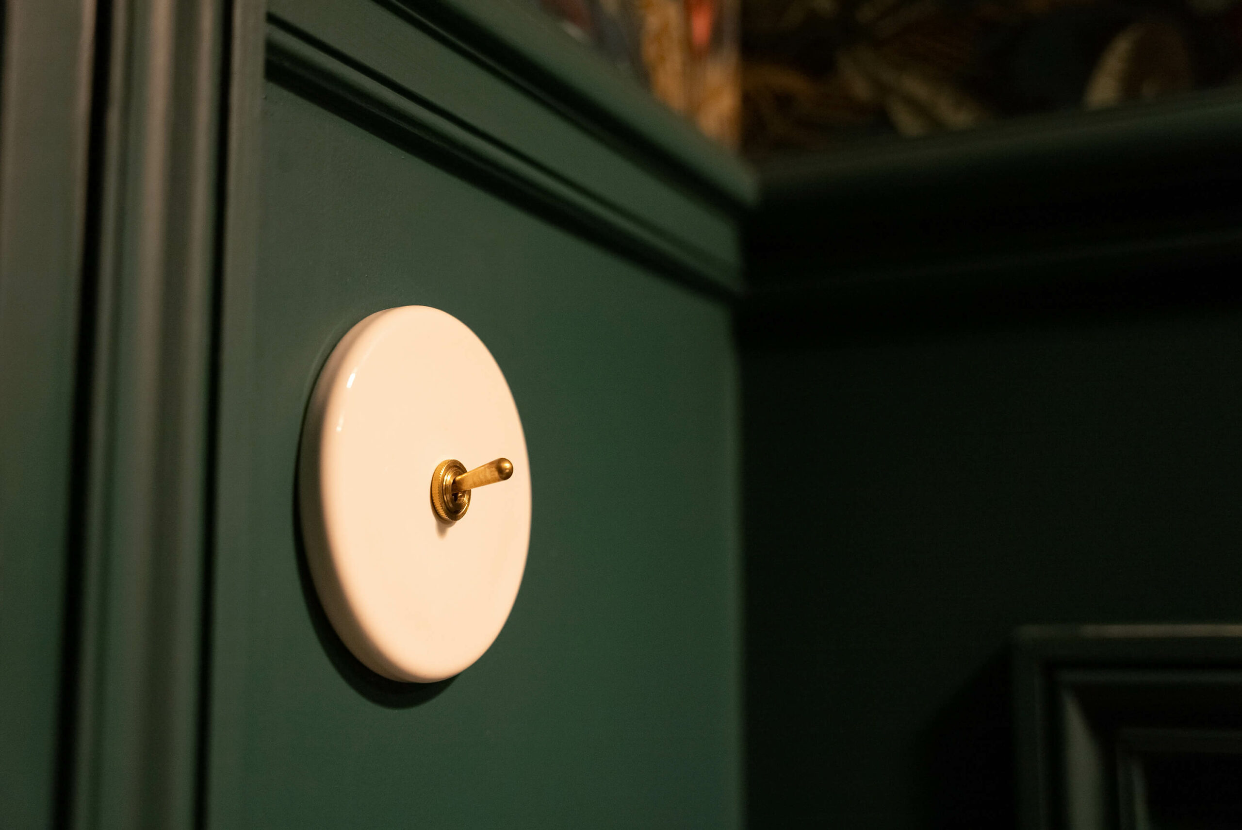 Rénovation d’une maison meulière à Bonnières, toilettes cabinet de curiosité avec soubassement mouluré vert foncé et papier peint tropical, miroir pivotant laiton ancien