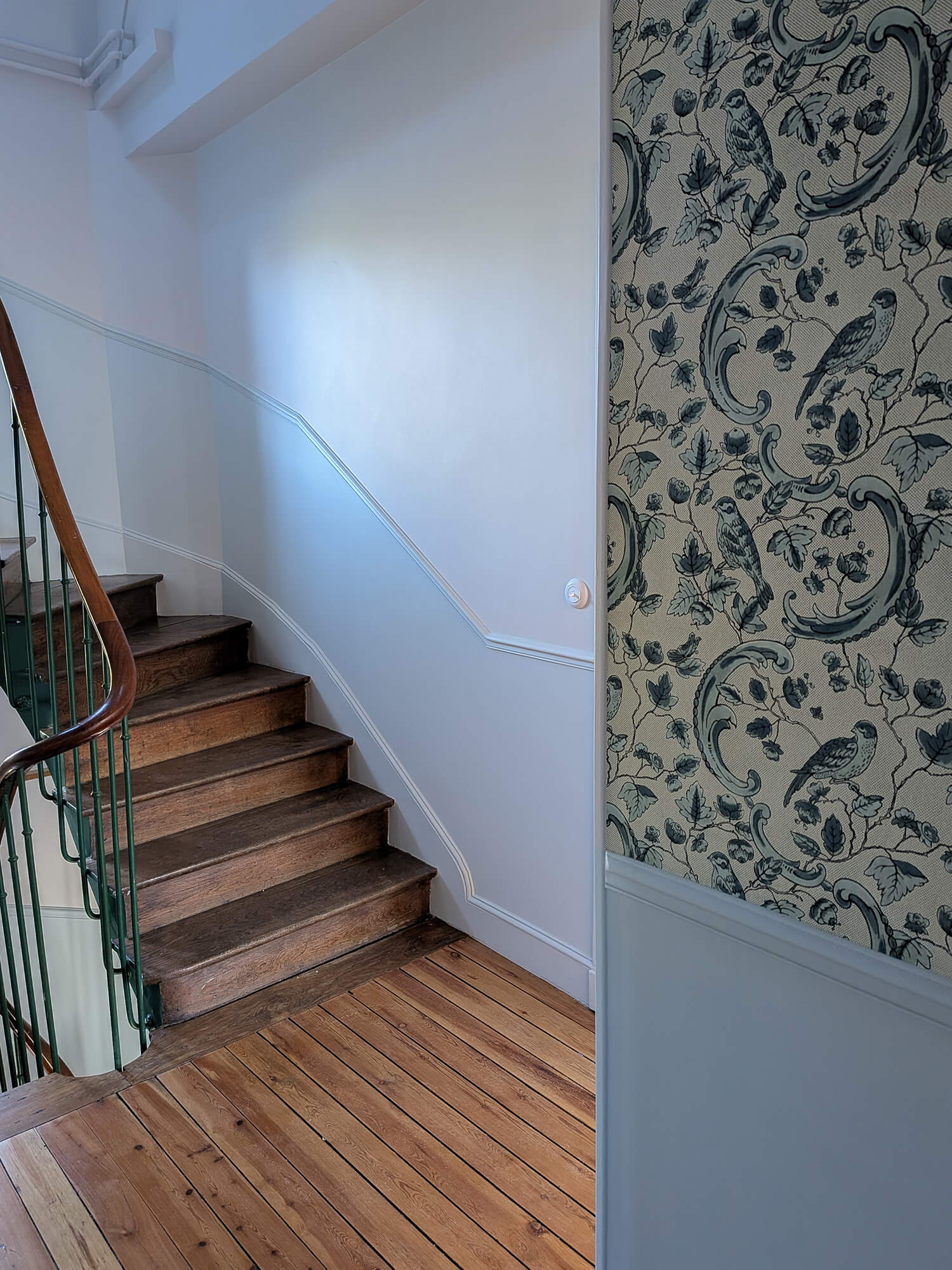 Rénovation d’une maison meulière à Bonnières, retrouver le charme de l’ancien, palier avec soubassement bleu clair et cimaises, papier peint effet toile de jouy bleu