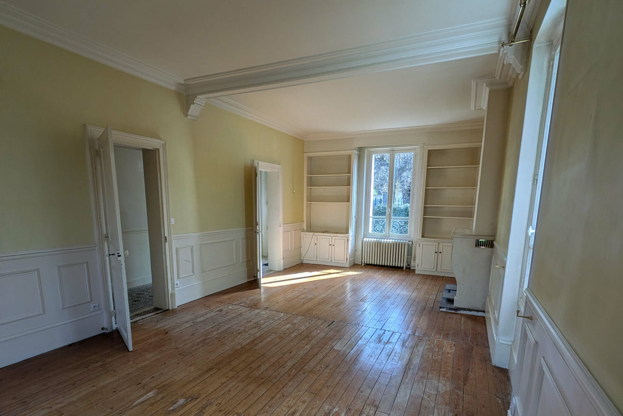 Rénovation d’une maison meulière à Bonnières, retrouver le charme de l’ancien, photo avant du double séjour avec bibliothèque et murs jaunes