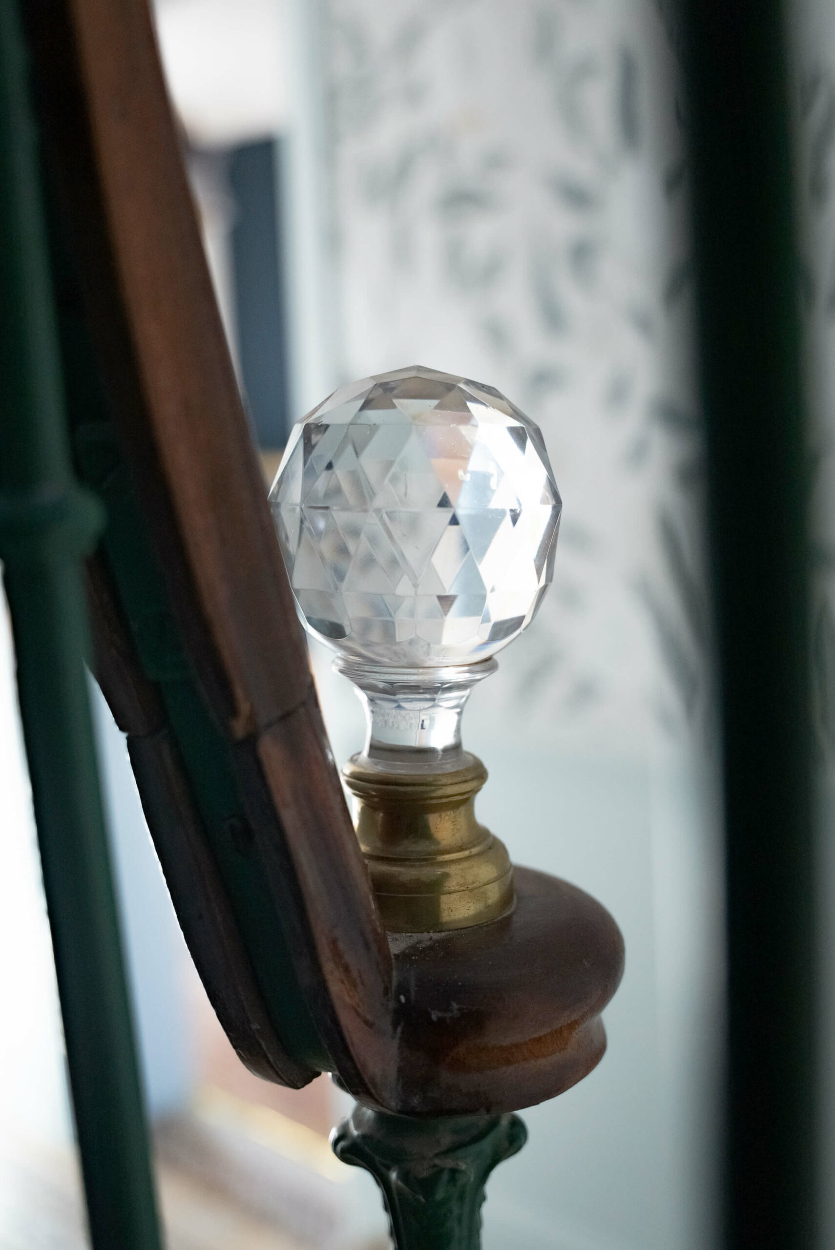 Rénovation d’une maison meulière à Bonnières, retrouver le charme de l’ancien, pommeau d'escalier en verre sublimé et laiton, papier peint floral bleu ciel en arrière plan