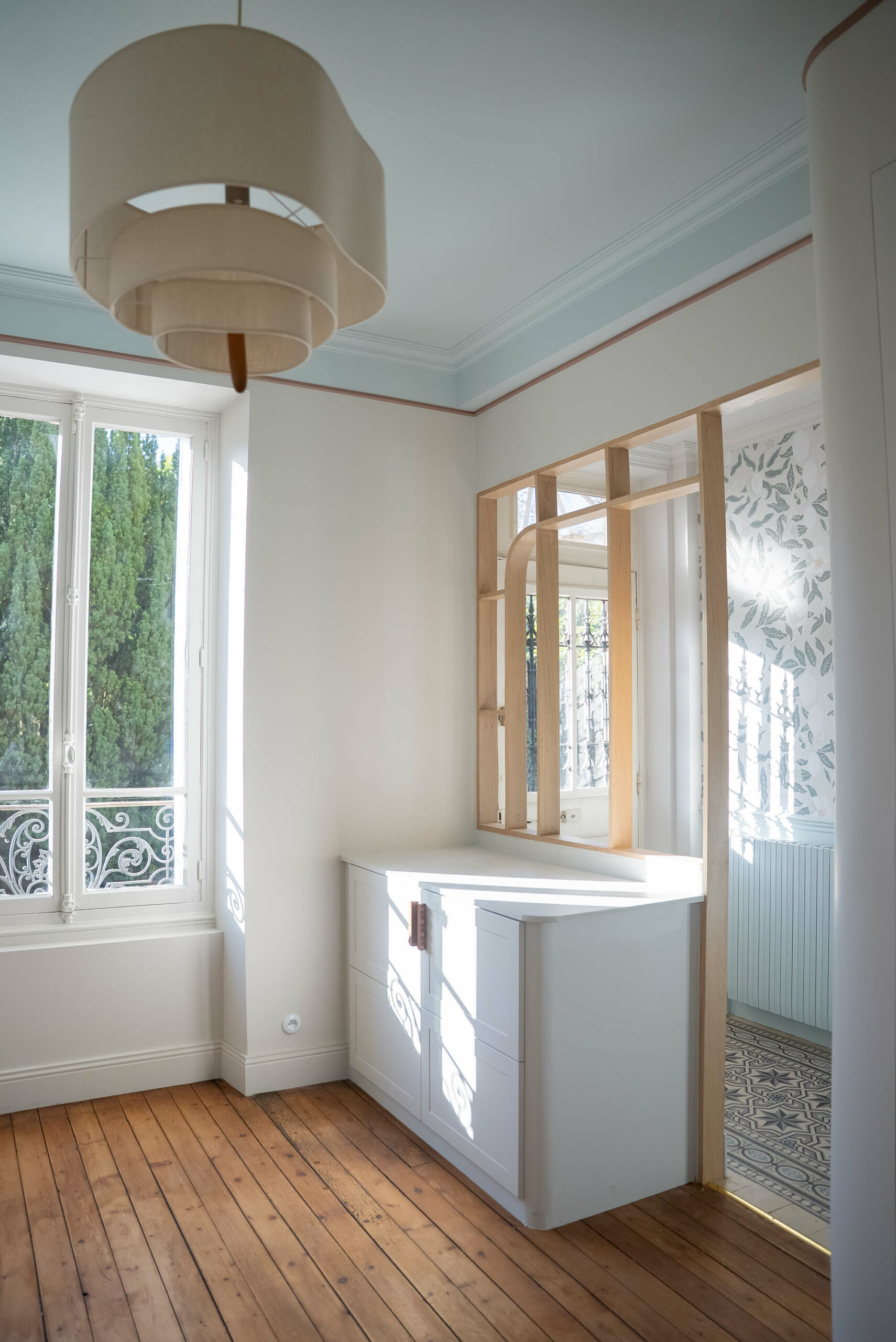 Rénovation d’une maison meulière à Bonnières, retrouver le charme de l’ancien, vestiaire avec parquet ancien, meuble sur mesure et claustra bois, tons beiges et bleu ciel avec un papier peint bleu à fleurs