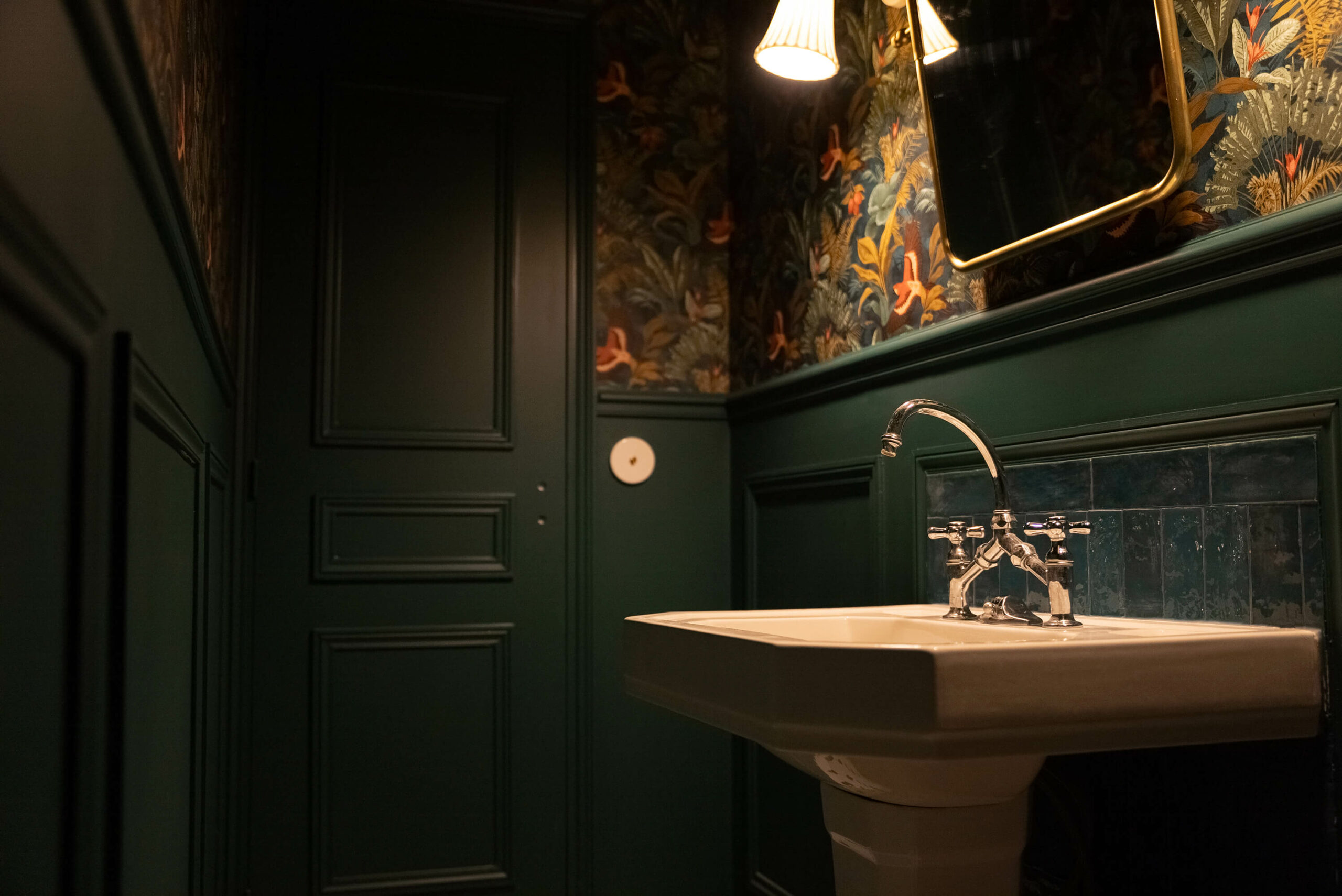 Rénovation d’une maison meulière à Bonnières, toilettes cabinet de curiosité avec murs moulurés vert foncé, papier peint tropical, zelliges vert foncé