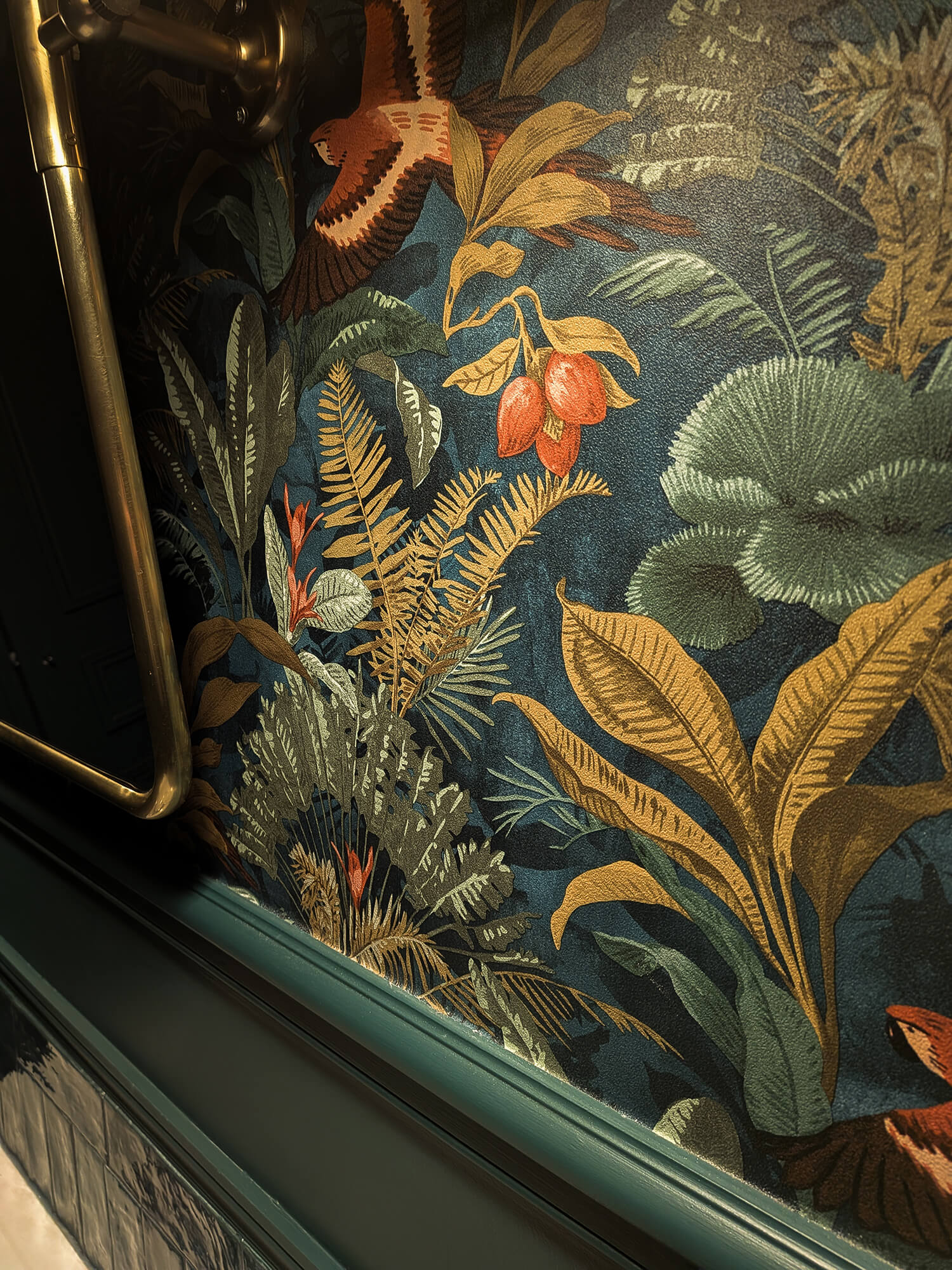 Rénovation d’une maison meulière à Bonnières, toilettes cabinet de curiosité avec soubassement mouluré vert foncé et papier peint tropical, miroir pivotant laiton ancien